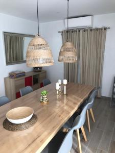 uma sala de jantar com uma mesa de madeira e 2 lustres em Les Agapanthes em Noirmoutier-en-l'lle