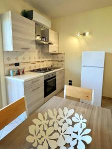 a kitchen with a table and a white refrigerator at Appartamento vicino aeroporto d'Abruzzo in San Giovanni Teatino