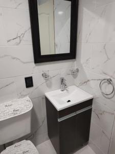 uma casa de banho branca com um lavatório e um espelho em M&M DEPARTAMENTO em El Calafate