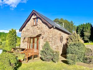 a small brick house with a table and a chair at Cedar Barn in Llangwm-isaf