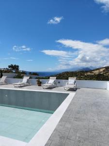 a group of lounge chairs on the roof of a house at Villa George Sea View with pool - Triopetra in Triopetra