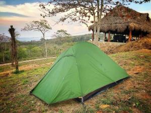 a green tent in a field next to a hut at Ecohotel La Reserva in Piojó