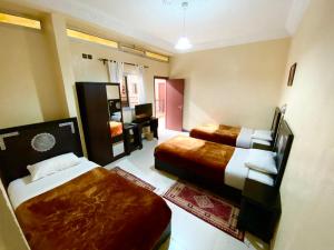 een hotelkamer met 2 bedden en een televisie bij Hôtel Narjisse in Marrakesh