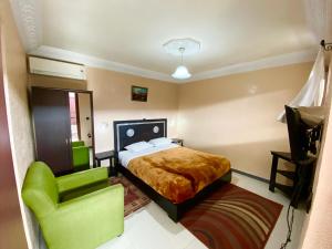 a bedroom with a bed and a green chair at Hôtel Narjisse in Marrakech