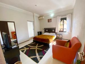 um quarto com uma cama, um sofá e uma cadeira em Hôtel Narjisse em Marraquexe