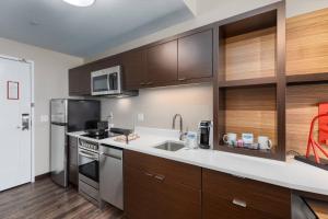uma cozinha com armários de madeira e electrodomésticos de aço inoxidável em TownePlace Suites by Marriott Owensboro em Owensboro