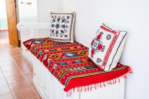 a white bench with a colorful blanket and pillows on it at Olive Grove Cottage in Karpathos Town