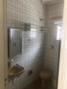 a bathroom with a sink and a toilet and a mirror at Apartamento no edifício Abaeté in Mongaguá