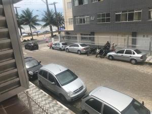 un gruppo di auto parcheggiate sul lato di una strada di Apartamento no edifício Abaeté a Mongaguá