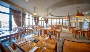 a restaurant with wooden tables and chairs and windows at Lazaat Hotel in Hull