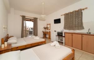 a bedroom with two beds and a kitchen with a sink at Tsimiklis Apartments in Finikounta