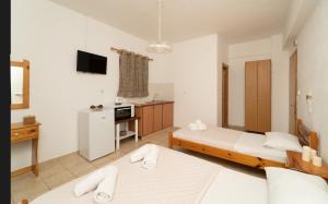 a hotel room with two beds and a kitchen at Tsimiklis Apartments in Finikounta