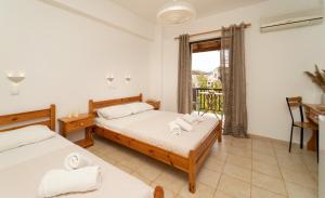 two beds in a room with a window at Tsimiklis Apartments in Finikounta