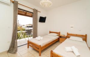 two beds in a room with a balcony at Tsimiklis Apartments in Finikounta