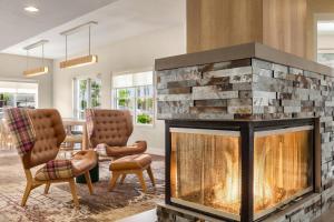 a fireplace in a living room with two chairs at Residence Inn by Marriott Palmdale Lancaster in Palmdale