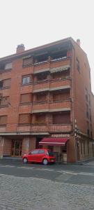 a red car parked in front of a brick building at maitzegur etxea in Echarri-Aranaz