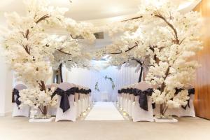 a wedding aisle with white flowers and chairs at Lazaat Hotel in Hull