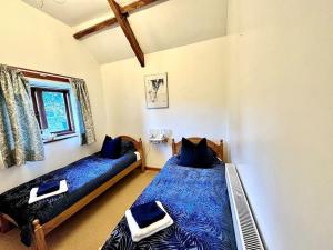 Llangwm-isaf的住宿－Detached ONE LEVEL stone barn (Rowan Cottage)，一间卧室设有两张带蓝色床单的床和窗户。
