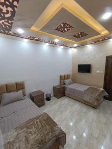 Petra downtown house في وادي موسى: غرفة نوم بسريرين وتلفزيون بشاشة مسطحة