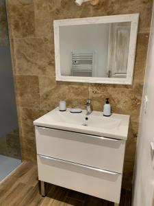 bagno con lavandino bianco e specchio di Maison de village pierrerue a Pierrerue
