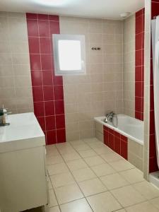 een badkamer met rode muren, een bad en een wastafel bij Maison piscine 4 ch Carcans Médoc Bassin Arcachon in Carcans