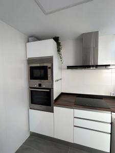 a kitchen with white cabinets and a microwave at Acogedora y moderna casa en pueblo in Serra