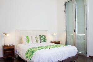 a bedroom with a large white bed with green pillows at Hotel Casa de la Vega in Bogotá