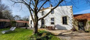 a white house with a tree in the yard at Au Logis de la Mongie in Soullans