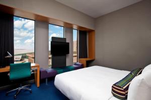 a hotel room with a bed and a desk and a window at Aloft Tulsa Downtown in Tulsa