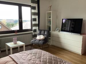 sypialnia z łóżkiem, telewizorem i krzesłem w obiekcie Haus Hunsrückhöhe w mieście Schauren