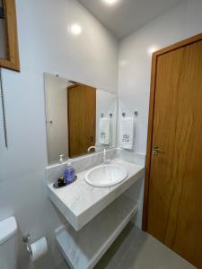 un bagno bianco con lavandino e specchio di Suítes no Paraíso a Espera Feliz Altre 14 foto