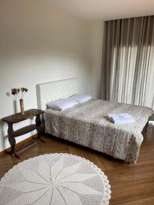 - une chambre avec un lit, une table et un tapis dans l'établissement Suítes no Paraíso, à Espera Feliz