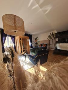 a large living room with a couch and a tub at Escapade Mâconnaise Spa-Sauna-Ciel de pluie tropicale-Champagne Nuit Romantique in Mâcon