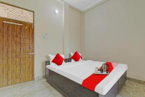 a bedroom with a bed with red pillows and a wooden door at Flagship Pratap Guest House in Sultānpur