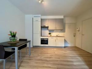 Una cocina con gabinetes blancos y una mesa con sillas. en Studio hypercentre Bruxelles, en Bruselas
