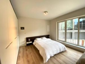 Un dormitorio con una cama blanca y una ventana grande. en Studio hypercentre Bruxelles, en Bruselas