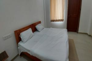 a bed with white sheets and pillows in a bedroom at SPOT ON Shyam Dharamshala in Haridwār