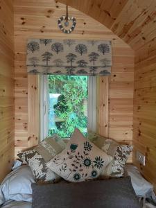 a bedroom with a large window in a log cabin at A Unique & Tranquil Smallholding Retreat in Redruth