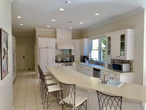 a kitchen with white cabinets and a counter with chairs at 7000 sf: 5 king / 1 queen / 7 single beds, heated pool/spa, designer furnishings in Flowery Branch