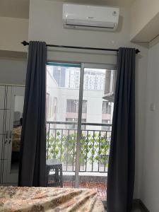 een slaapkamer met een raam met uitzicht op een balkon bij Apartemen Serpong Greenview Premium in Ciater-hilir