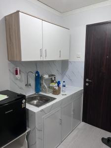 een keuken met witte kasten en een wastafel bij Apartemen Serpong Greenview Premium in Ciater-hilir