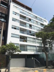 a tall white building with trees in front of it at Confortable and functional SUITE in MIRAFLORES ! in Lima