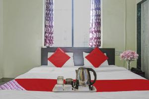 a bed with red pillows and a tea kettle on it at R K Exclusive in Hinjewadi