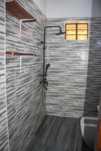 a bathroom with a shower with a toilet and a window at Villa Sunshine House ZANZIBAR in Jambiani