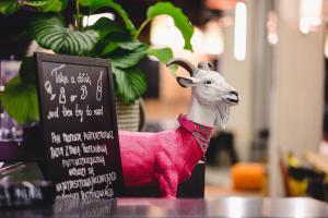 una cabra de juguete rosa al lado de una señal en Moxy Poznań Airport, en Poznan