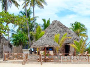 een hut op het strand met palmbomen bij Villa Sunshine House ZANZIBAR in Jambiani