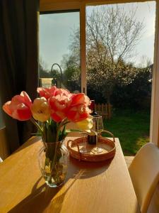 een vaas met bloemen op een tafel met een raam bij La Closerie de Thimécourt in Luzarches