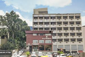 Un grand bâtiment avec des voitures garées dans un parking dans l'établissement Townhouse OAK Utsav Residency, à Indore