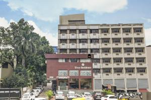 a tall building with cars parked in a parking lot at Townhouse OAK Utsav Residency in Indore