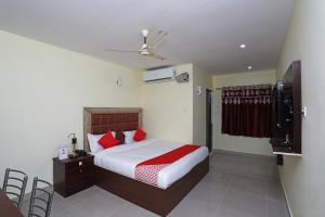 a bedroom with a bed with red pillows and a television at OYO Ma Classic Inn in Bhubaneshwar